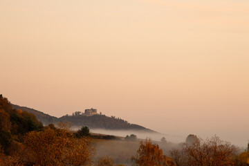 Hambacher Schloss im herbstlichen Sonnenaufgang mit Nebel und Wolken über dem Pfälzerwald