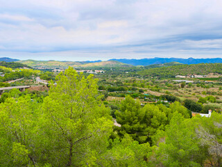 Obraz premium wide view of lush green hills and valleys fills landscape, with patches of trees and cloudy sky above. peaceful setting showcases beauty of rural nature and tranquility