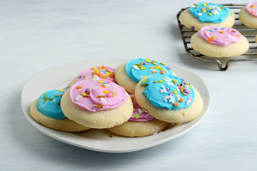 pink and blue sugar cookies on plate with more on cooling rack