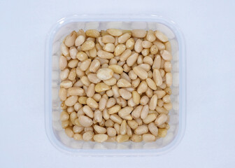 A plastic container filled with pine nuts