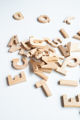 Scattered wooden alphabet letters on white surface for educational play