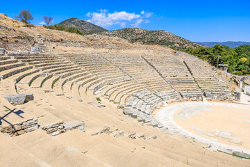A large stone amphitheater with a stage and a few benches. Ruins of the ancient city of Philippi,...