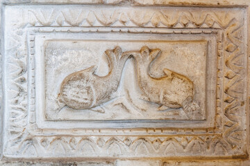 Ancient stone carving of birds in relief with geometric patterns. Fish as a symbol of Christianity