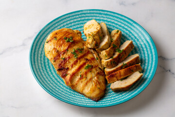 Grilled chicken breast slices served with mashed potatoes and vegetables.