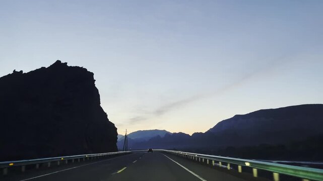 vehicle traveling on dark winding mountainous road in xinjiang, china