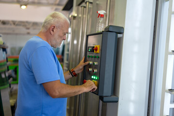 An elderly worker controls the process of installing glass in PVC frames.