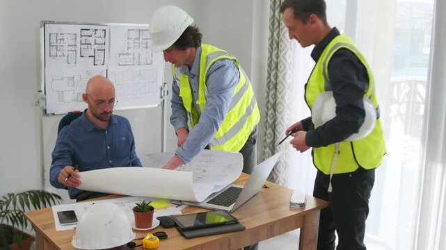 caucasian engineer pointing out changes on large plan at desk, two contractors observing, hardhat and measuring tape on table, papers scattered, engaged expressions, detailed revision process