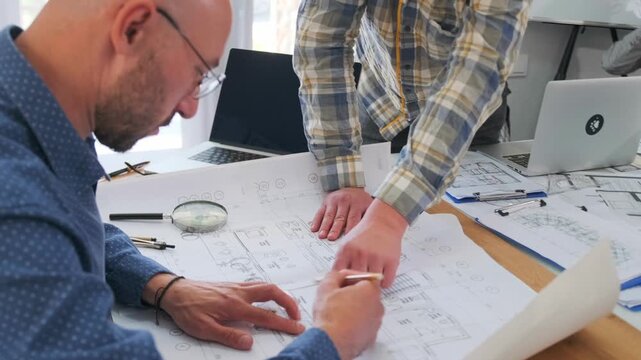 designers reviewing plans, architect and writer finalize design, collaborative review of blueprint in bright workspace, team working together on architectural plans with tools and technology