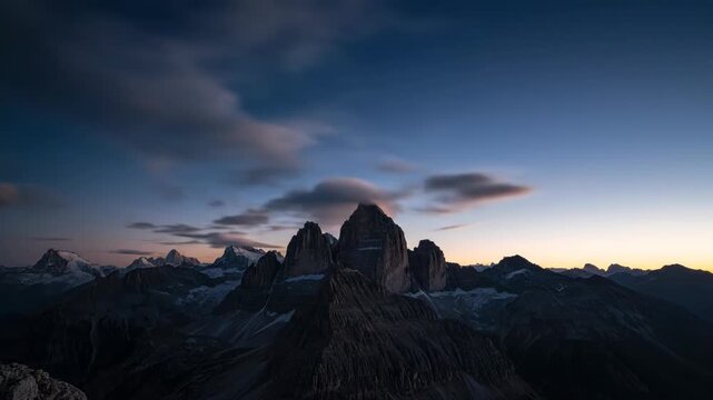 Mountain peaks silhouetted against a vibrant twilight sky with clouds