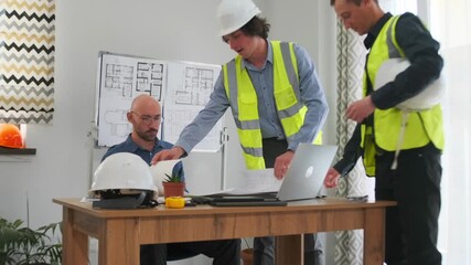 caucasian foreman presenting large blueprint to seated client, two contractors standing, helmet on desk, light filled room, detailed floorplans on wall, attentive client response, collaborative review