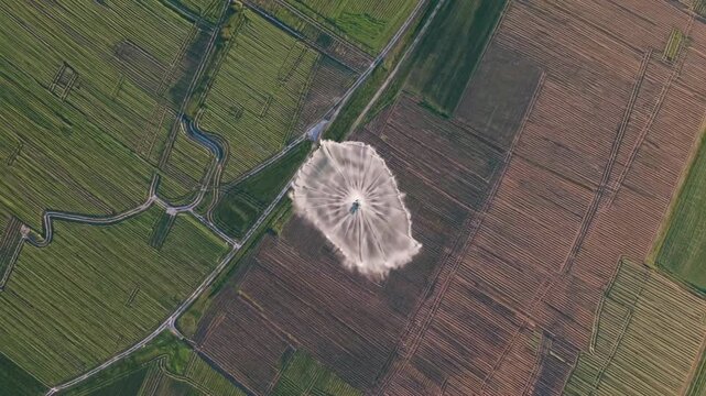Aerial drone perspective revealing center pivot irrigation system spreading water across vast farmland, highlighting advanced agricultural technique for optimal crop management