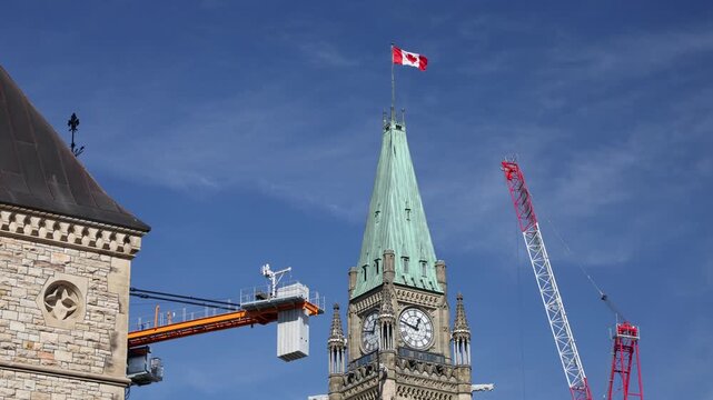 Peace Tower at Parliament Hill with construction cranes and Canadian flag