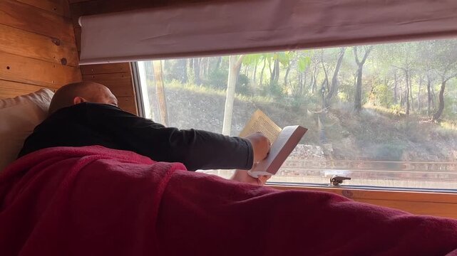 Hombre leyendo en la cama de la caravana 4K