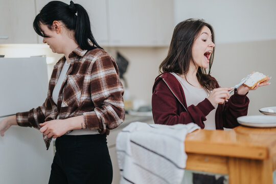 Closeup of two friends having fun and cooking together in a home kitchen - Powered by Adobe