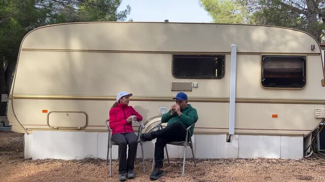 Pareja tomando caf&eacute; frente a la caravana 4K