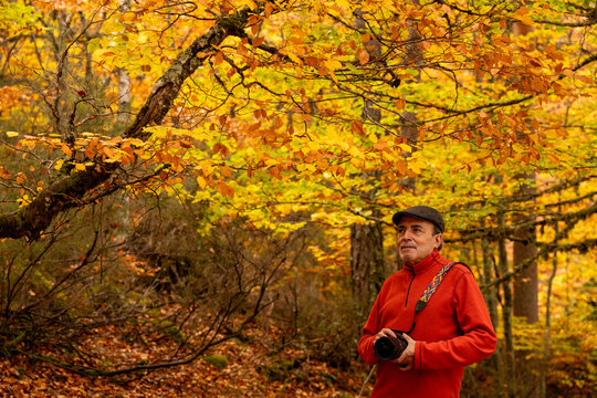 Man with camera exploring vibrant autumn forest - Powered by Adobe