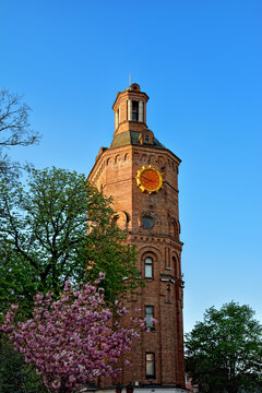 Brick tower with a large clock against the blue sky.