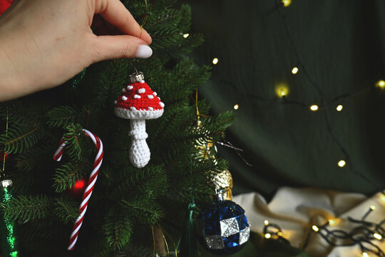 Merry Christmas. New year's toy in hand. Knitted red fly agaric mushroom to decorate the Christmas tree. DIY toys. Holiday with children. Cozy home on Christmas eve. Retro style. Retro Christmas
