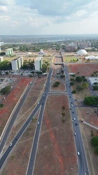 Imagem a&eacute;rea vertical revela avenida que cruza a cidade, com fluxo constante de ve&iacute;culos, &aacute;reas verdes e quadras organizadas, representando urbanismo planejado e din&acirc;mica cotidiana