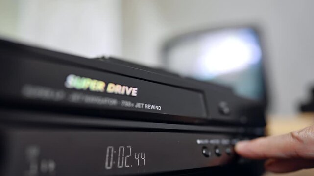 Front panel of the DVD player. Hand presses the button on the device. Close up.