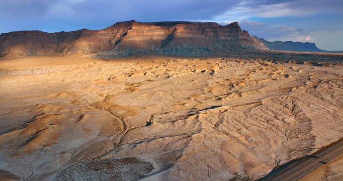 Drone shot of Utah desert mesa and eroded terrain with warm evening light highlighting textures and shadows.