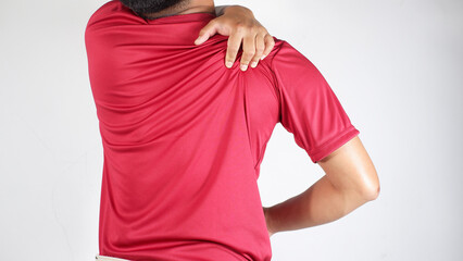 Young man with back pain touching his upper back, Stiff and sore shoulders. Back injury. Man giving himself a massage on his upper back
