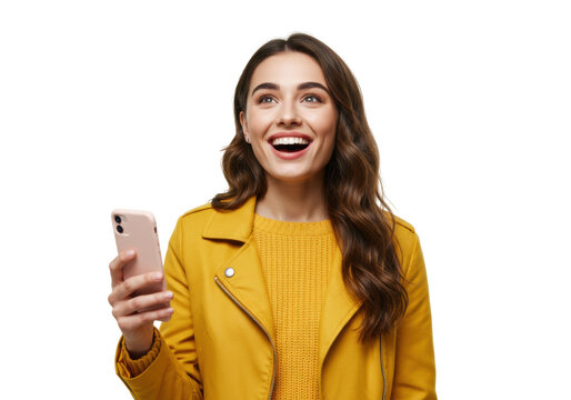 Excited young woman with phone isolated on white, happy girl in yellow jacket looking up with joy and holding smartphone