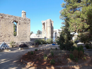 Courtyard of medieval monastery ruins in Cyprus with ancient stone walls, arched windows,...