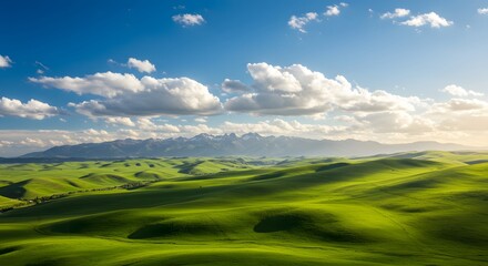 Obraz premium Rolling green hills under a bright blue sky with scattered white clouds