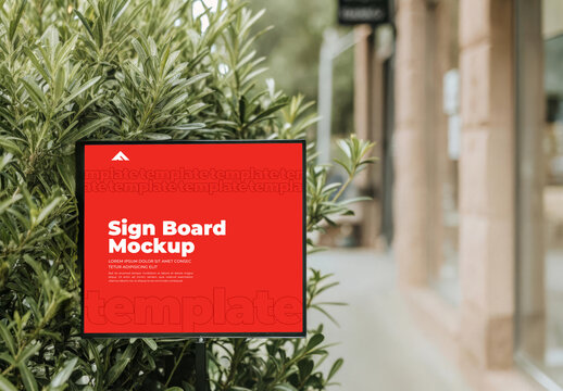 Vertical Sign Board Mockup on Building Wall Surrounded by Green Plants and Leaves