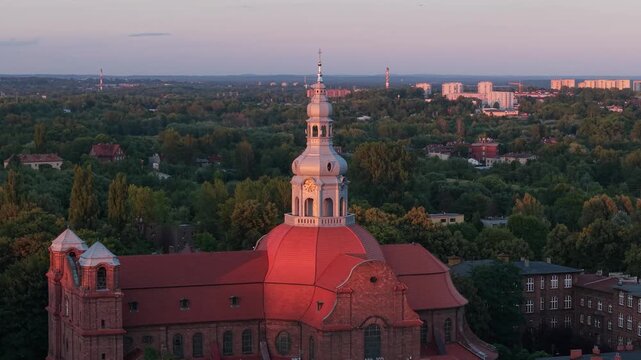Aerial drone footage of Nikiszowiec district in Katowice, Poland, during a beautiful sunset. Historic red brick buildings glowing in golden light, showcasing unique urban architecture.