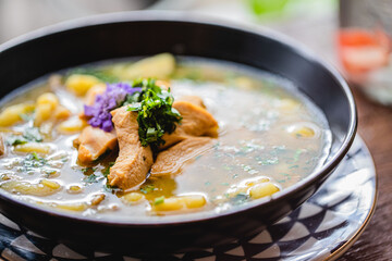 Chicken soup with corn and a purple flower for garnish at a modern well lit health food restaurant