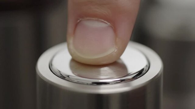Finger pressing a metallic button on a cylindrical object