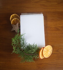 Christmas decor, mock up wih empty white paper sheet, with snowy pine wreath, on wooden background
