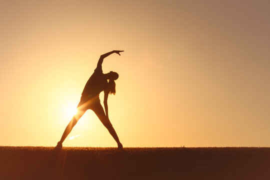 Woman doing yoga stretch at sunset, body health, exercise and balance.