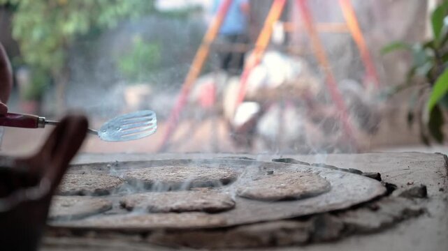 Corn tortillas cooking on a clay comal in an outdoor Mexican kitchen, Mexican food