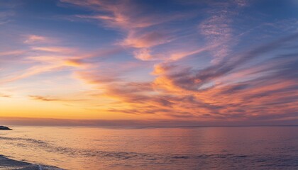 Obraz premium Morning sky with glowing cirrus clouds over calm ocean water at sunrise 