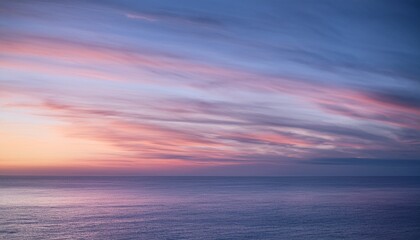 Evening sky with purple cirrus clouds over calm ocean water at sunset
