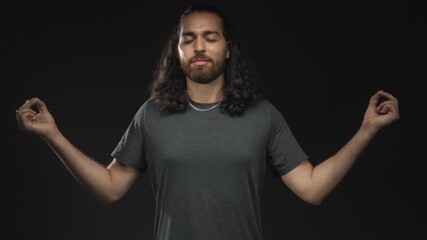 Man, young arab hispanic with long hair and beard, hands in meditation mudra and closed eyes in studio on black backdrop; calm mindfulness. - Powered by Adobe