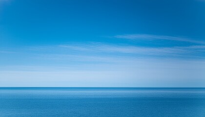 Fototapeta premium Bright blue sky with cirrus clouds over calm ocean water in the daytime 