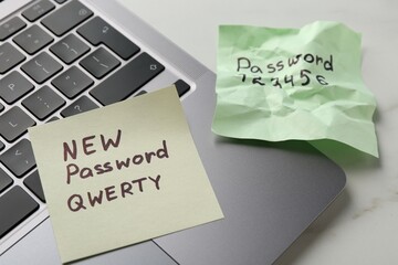 Changing password. Paper notes with new and old passwords and laptop on white table