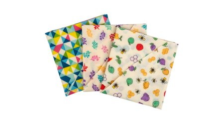 Three beeswax food wraps with different patterns stacked on a white background