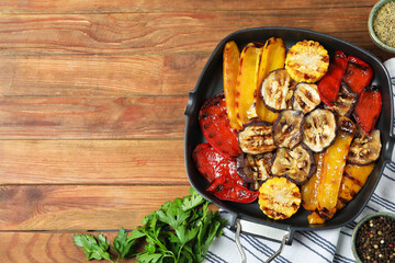 Tasty grilled vegetables in pan, spices and parsley on wooden table, flat lay. Space for text