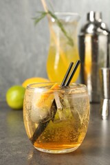 Glasses of tasty cocktails, shaker and jigger on grey table, closeup