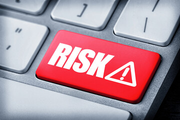 Red button with word Risk and warning sign on computer keyboard, closeup