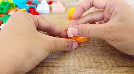 Fototapeta premium an asian woman is playing with lego forming the legs to form a giraffe with a brown background