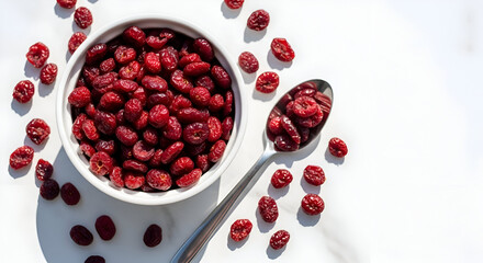A photo of dried cranberries in a bowl and spoon on a white background