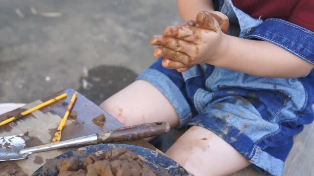 Little child's hands kneading and molding a lump of clay on a spinning wheel, creating earth ware