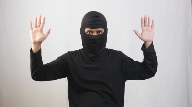 thief wearing a black mask raised both hands to surrender