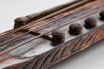 Close-up of stringed wooden instrument's detailed headstock, tuning pegs, and strings, on white
